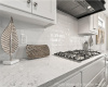 Kitchen featuring ventilation hood, tasteful backsplash, stainless steel gas stovetop, and white cabinetry