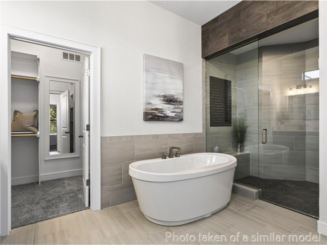 Bathroom featuring tile walls, a freestanding tub, and a stall shower