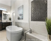 Bathroom with a freestanding bath, vanity, and tile walls