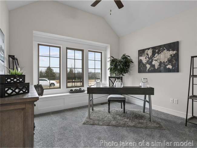 Home office featuring ceiling fan, carpet flooring, and lofted ceiling