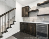 Indoor wet bar featuring beverage cooler, decorative backsplash, stairway, and dark tile patterned floors