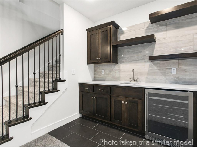 Indoor wet bar featuring beverage cooler, decorative backsplash, stairway, and dark tile patterned floors