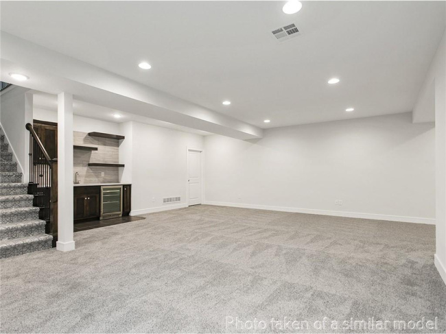 Finished basement with carpet flooring, recessed lighting, stairs, beverage cooler, and bar area