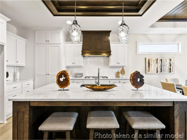 Kitchen with a tray ceiling, a breakfast bar area, light wood-style floors, and white cabinets